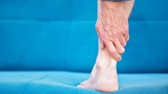 A person holding their painful Achilles tendon.