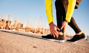 A person in exercise clothes holding the outside of their foot and ankle.