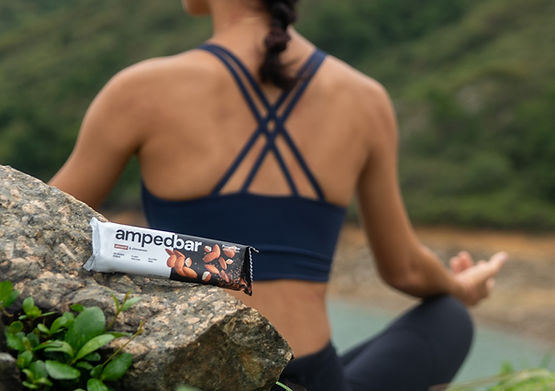 Woman in yoga poses holding Amped Bar in natural outdoor setting