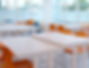 Classroom with orange and blue chairs and white tables