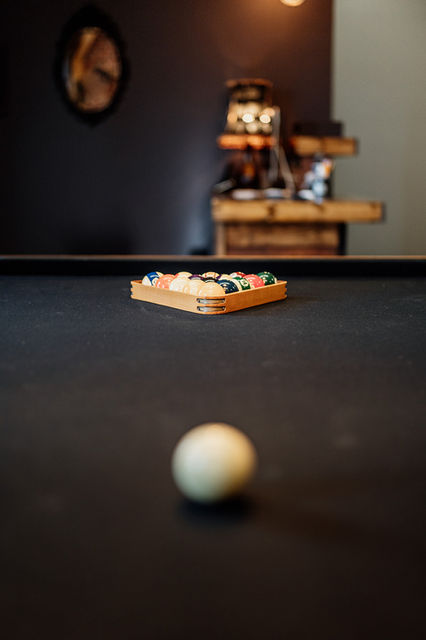 Inside the Speakeasy Gallery waiting room. Focus is centered on racked pool balls with an out of focus white ball at the bottom. The reception desk is visible in the background