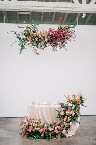 Suspended flowers over the bride and grooms sweetheart table with cascading table floral arrangements. 