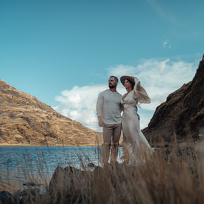 Couple standing by high-altitude lake during adventure elopement in Peru.