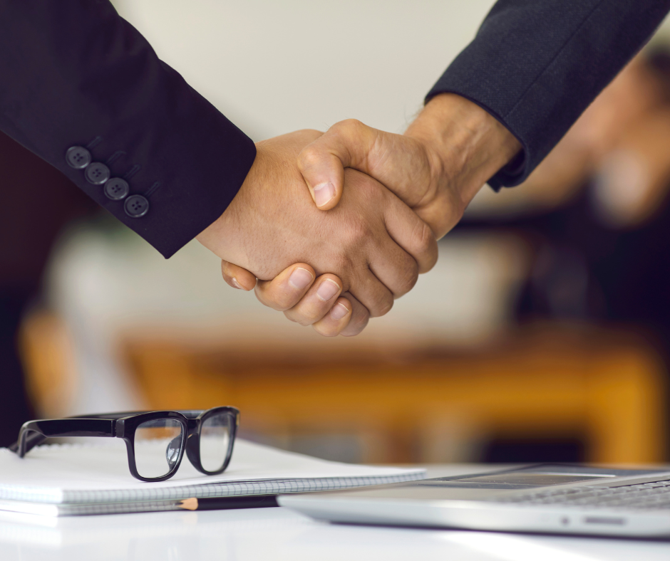 Shaking hands over glasses and notebooks