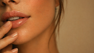 Close-up portrait of natural-looking lips with subtle definition and a soft, glossy finish.