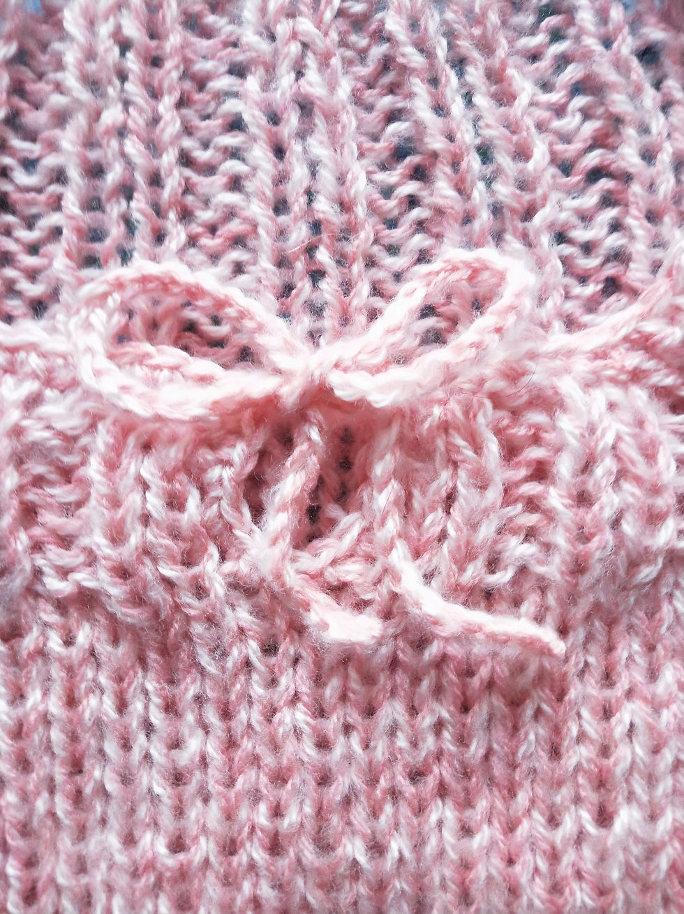 Photograph of pink knitted fabric with crochet bow detail