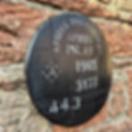 Angled close-up of black Ardbeg Distillery Islay 1965 whisky barrel cask head on a stone wall.