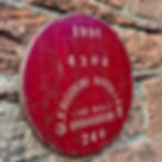 Angled close-up of red Glengoyne Distillery 1991 whisky barrel cask head on a stone wall.