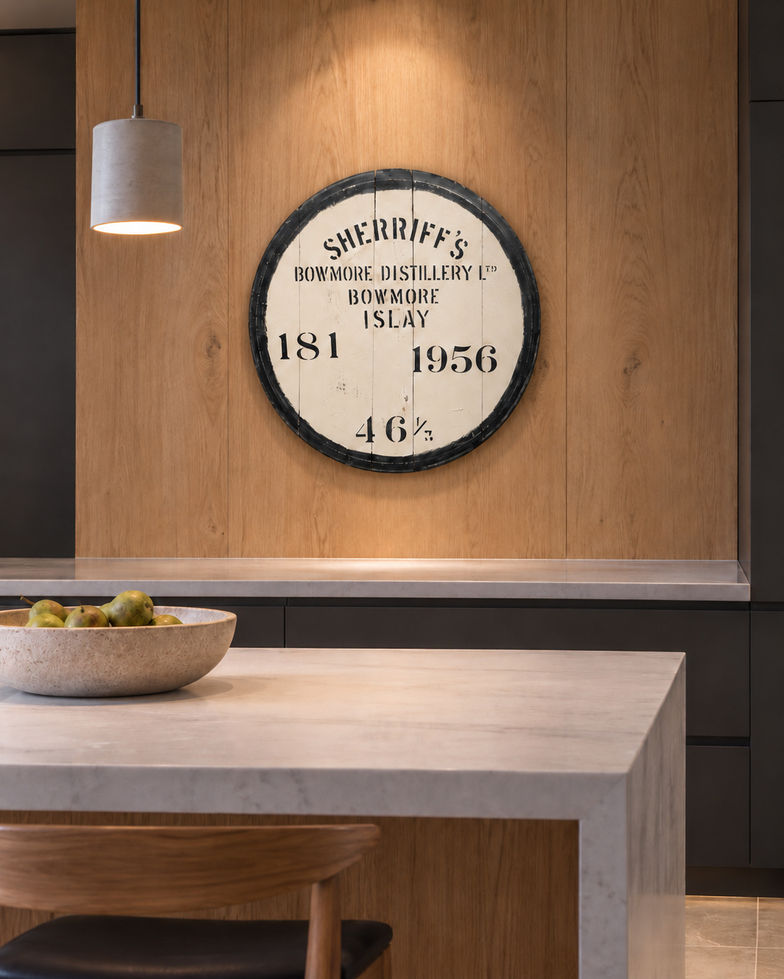 Bowmore 1956 barrel head with black lettering displayed above a counter in an oak-panelled kitchen.