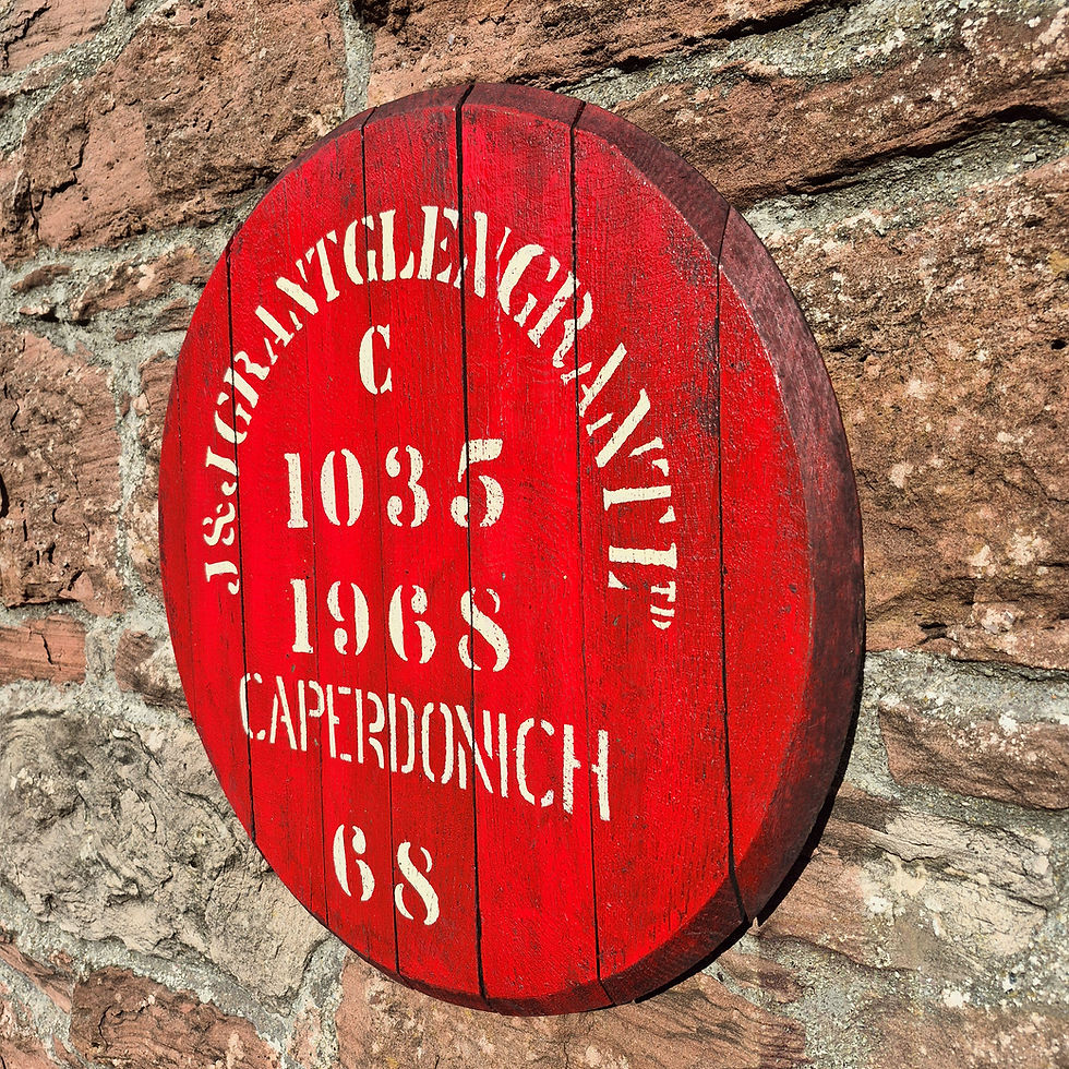 Angled view of the original Caperdonich 1968 cask head, showing its dark rim, red face and joined oak boards against stone.