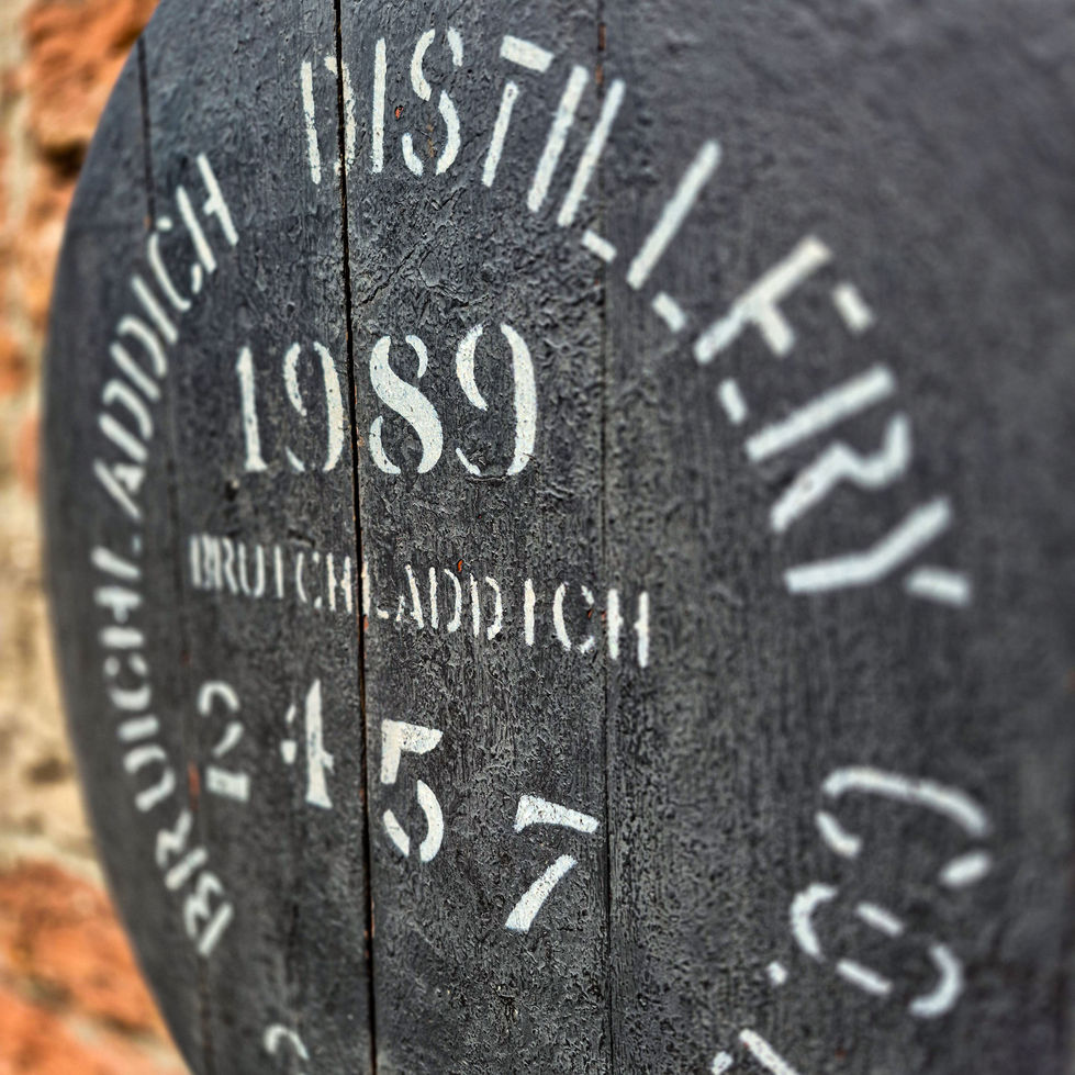 Angled close-up with shallow focus of a black Bruichladdich 1989 whisky barrel cask head.