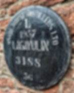 Side view of a black Lagavulin 1957 whisky barrel cask head stamped White Horse Distillers on a stone wall.