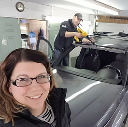 Image of the owners of Jason's Auto Glass, Jason is sealing a windshield in the background