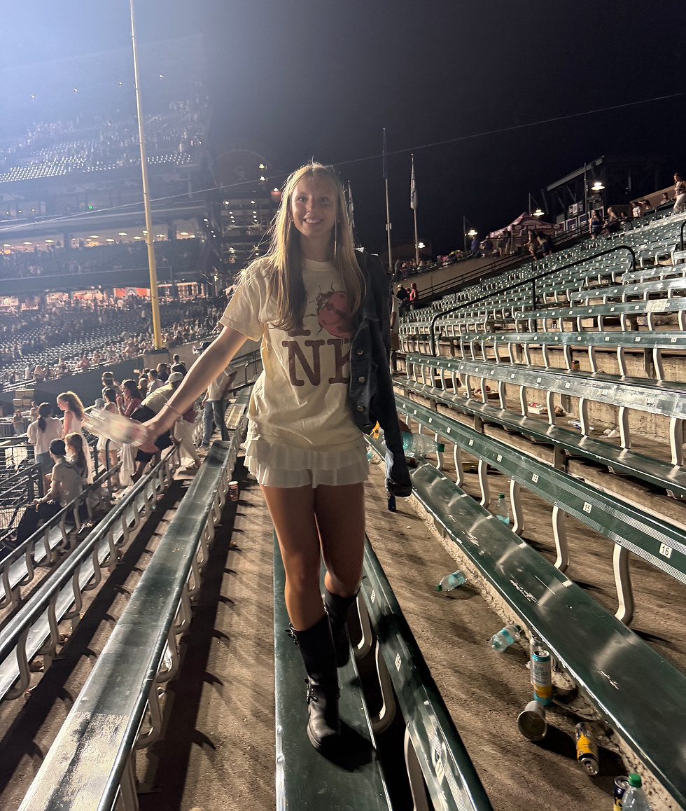 Portrait photo of Milly Messenbaugh standing in stadium bleachers at night with warm lighting