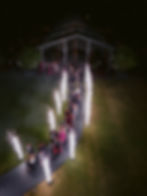 Nighttime wedding exit with fireworks and guests walking along an illuminated path.