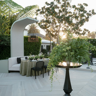 Cocktail area with luxury event rentals and sculptural arches at sunset in a garden venue