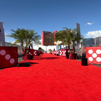 Red carpet entry with palm trees and dice decor leading to Arabian Champions Tour venue in Las Vegas.
