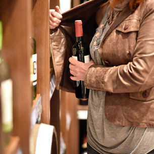 Woman shoplifting a bottle of wine