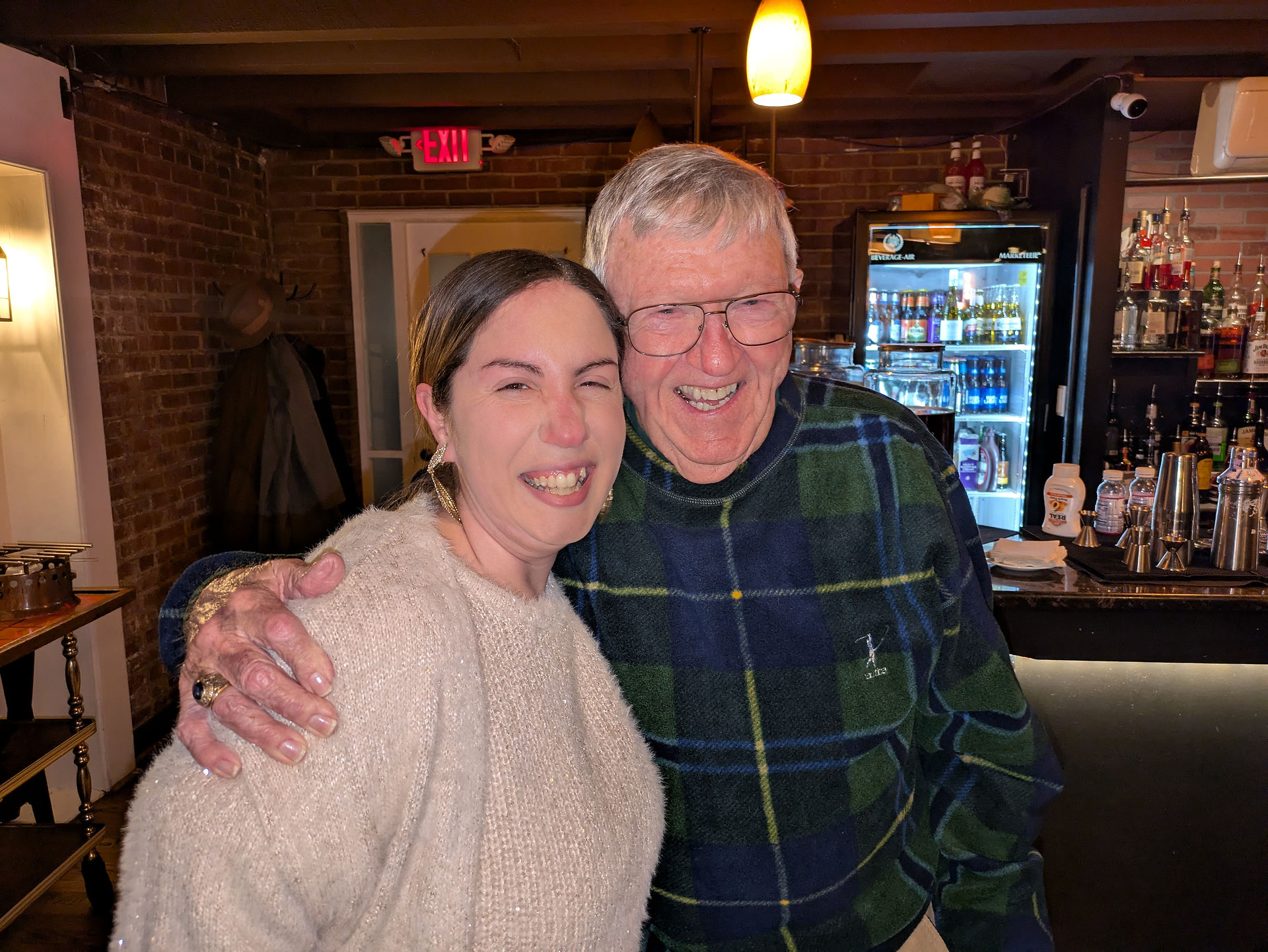 Happy woman and man embracing joyfully in a restaurant setting.