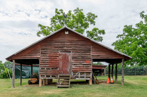 Weathered red wooden barn, steps, a small door, and a lawnmower.