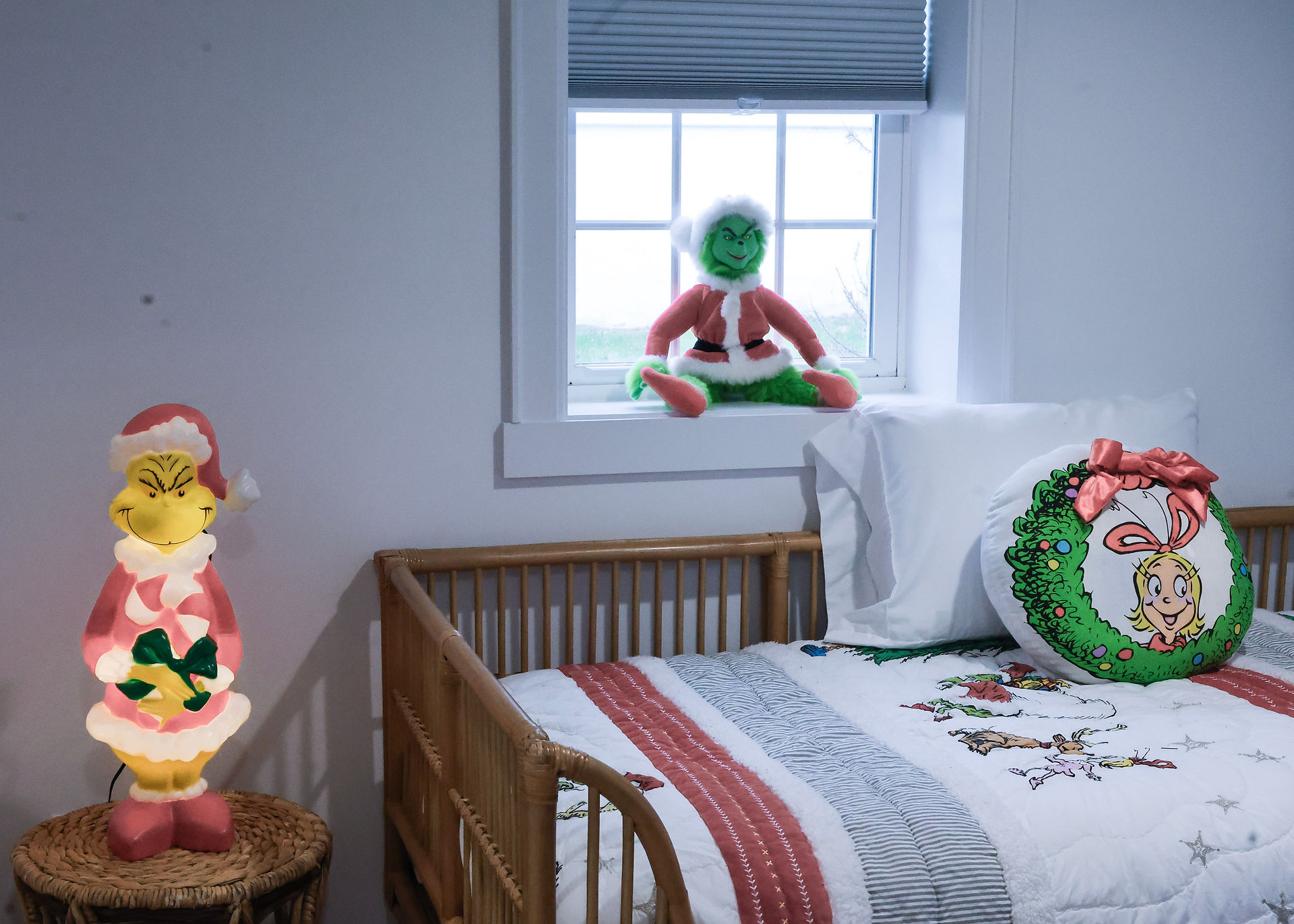 Grinch doll in window, Christmas bedroom scene, bed and wreath decorations.