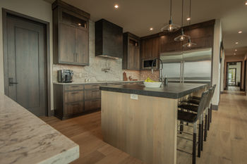 Modern kitchen with dark wood cabinets, light island, stainless appliances, pendant lights.