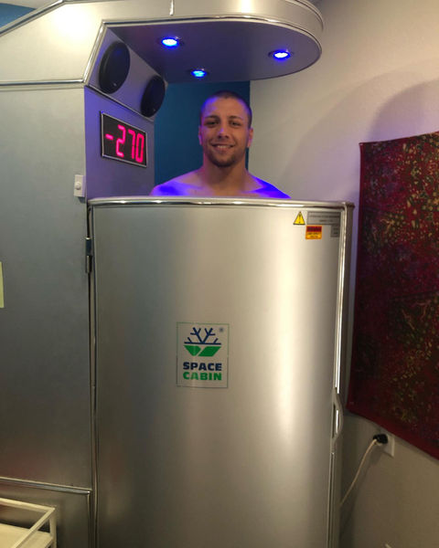 Man smiles in cryotherapy chamber, display shows -270
