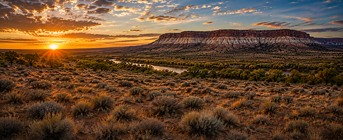 Sunrise over a desert mesa with a river in the foreground.
