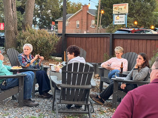 Group of adults chatting in Adirondack chairs outdoors