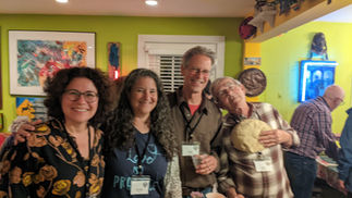 Four smiling attendees wearing badges at a lively indoor event.