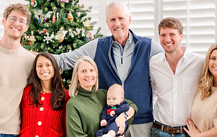 Smiling multi-generational family posing by a Christmas tree.