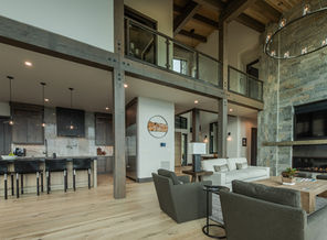 Spacious modern living room, kitchen, balcony, wood beams, and stone wall.