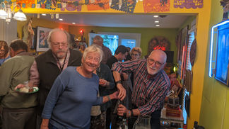 Smiling woman and man opening bottle at a cheerful indoor gathering.