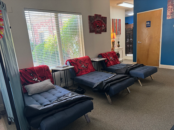 Three blue lounge chairs with red blankets in a waiting area.