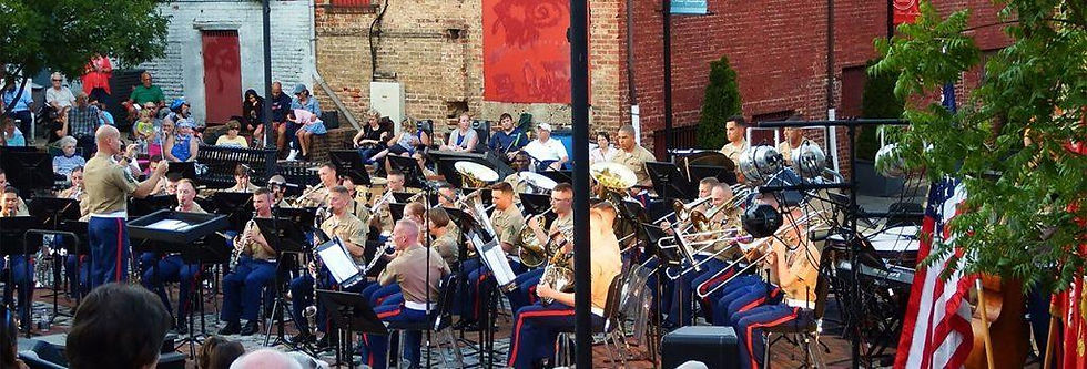 Outdoor performance by a military band with a conductor