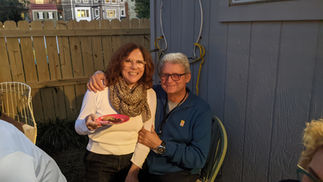 Smiling couple embracing outdoors at sunset, woman holds plate of food.