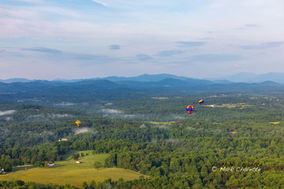 Hot air balloons over a misty forest and mountains