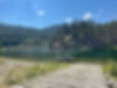 Boat ramp to a lake with a person in a small boat, forested hills