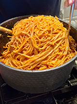Large pot of freshly cooked spaghetti coated in red sauce.