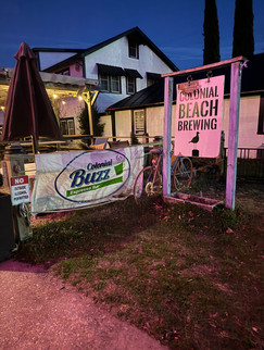 Colonial Beach Brewing sign and Colonial Buzz banner at dusk