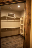 Empty walk-in closet with shelves, hanging rods, and wood-look flooring.