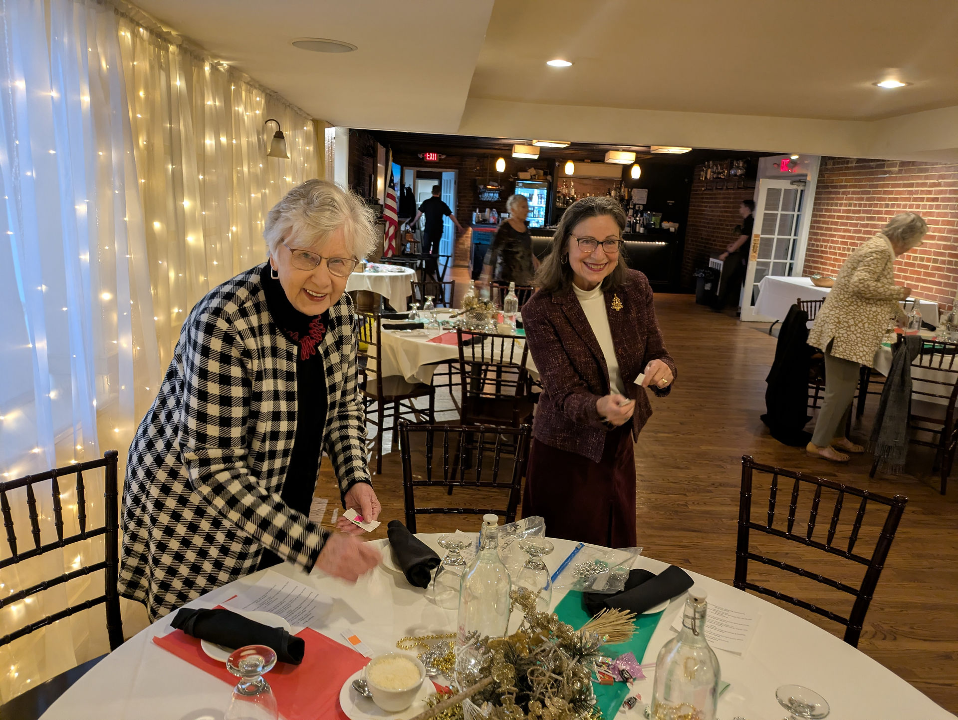Two women setting a table in a dimly lit dining room.