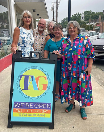 Group standing by a TAG gallery storefront open sign
