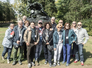 Group of smiling adults posing in front of a classical sculpture.