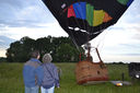 Two people watching a black and colorful hot air balloon