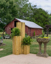 Wooden planters holding lush green plants, rustic red barn background.