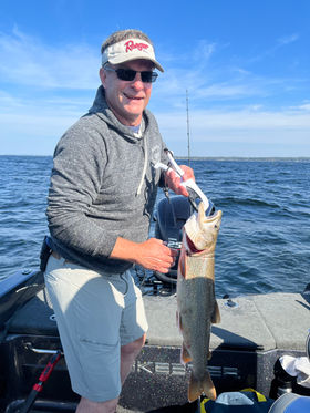 Man smiles while holding a fish on a boat in the water