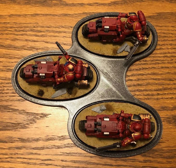 Miniature : Trois motos rouges sur une base, PROXY THOUSAND SONS CHAOS DREADNOUGHT, sur une surface en bois.