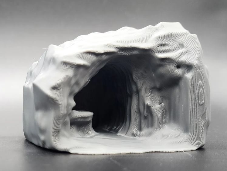 Une grotte blanche imprimée, entrée sombre, surface texturée, environnement extérieur. PRINTED ONLINE