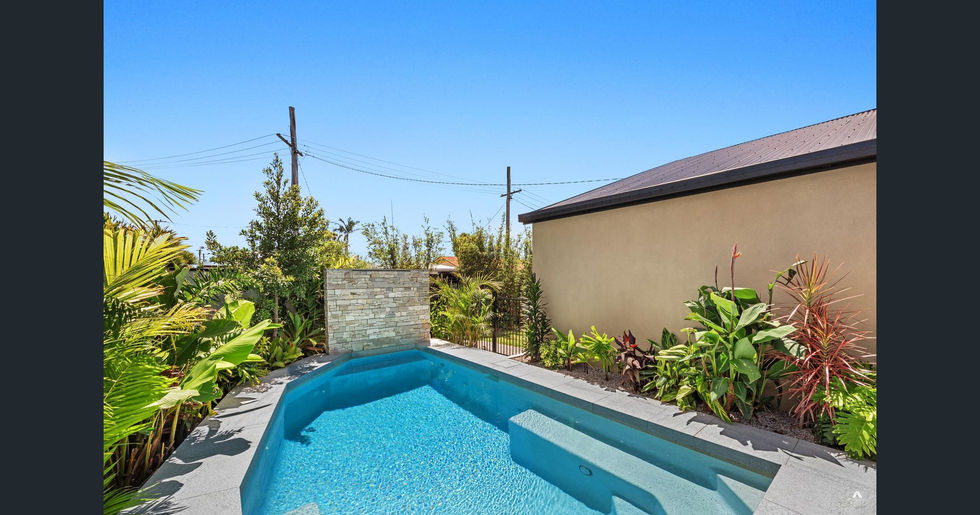 Custom shaped 6.0m x 3.2m concrete pool designed to maximise space along the fenceline. Features a 2m x 1.6m Features a 2.0m x 1.6m Thredbo wall-clad waterfall, Sand Drift Dropface Coping, Salt & Pepper Pebblecrete finish, and frameless glass fencing for an open, modern look.